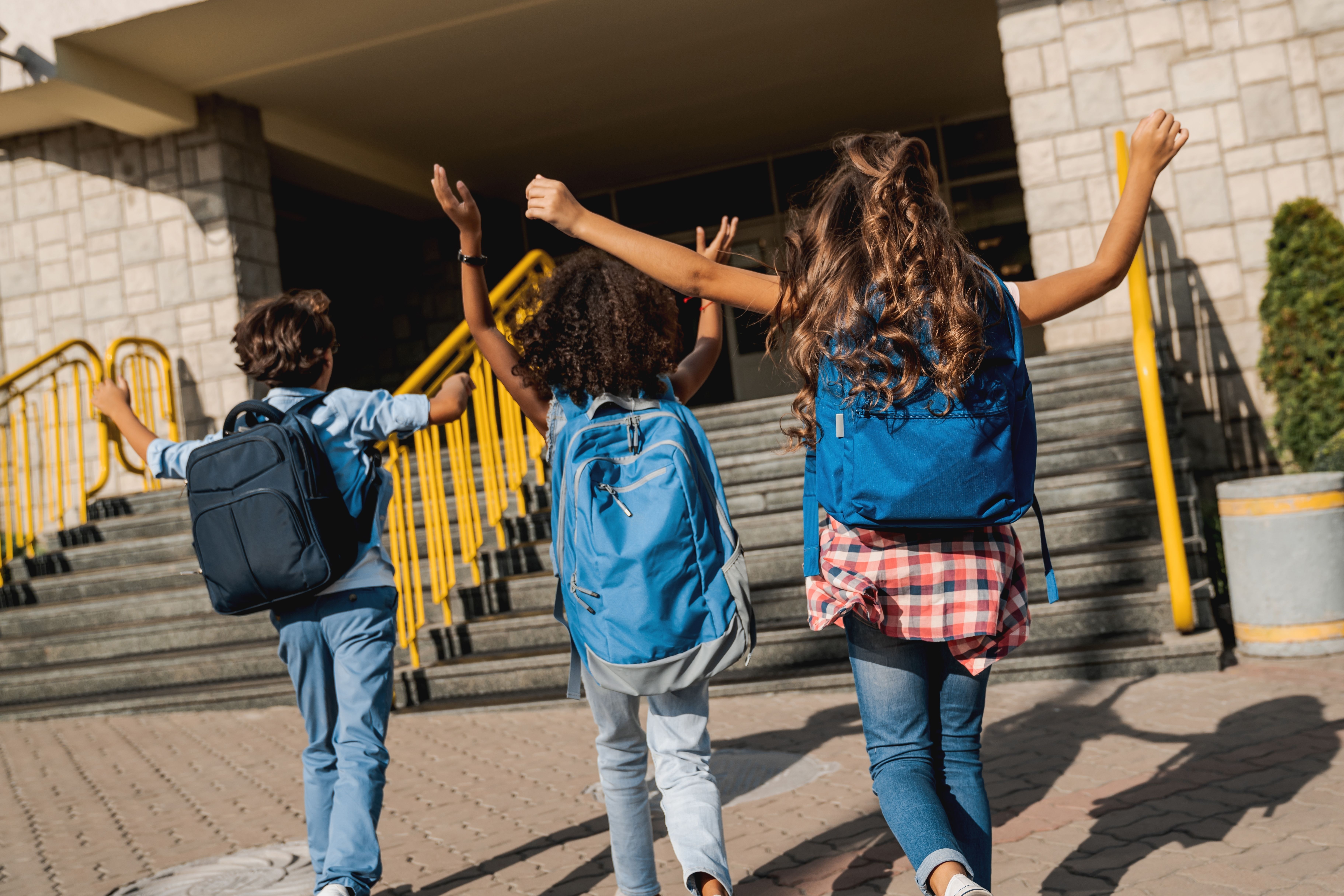 Groupe d’élèves heureux et divers marchant ensemble vers l’école